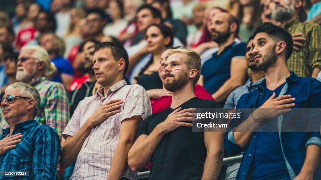 Povos em um estádio durante um hino nacional em um evento de esportes
