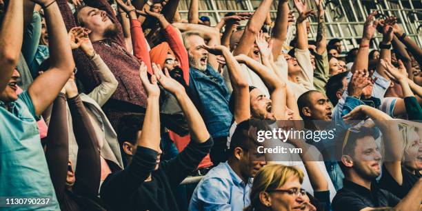 people doing a mexican wave on the tribunes - enthusiastic crowd cheering and doing the wave stock pictures, royalty-free photos & images