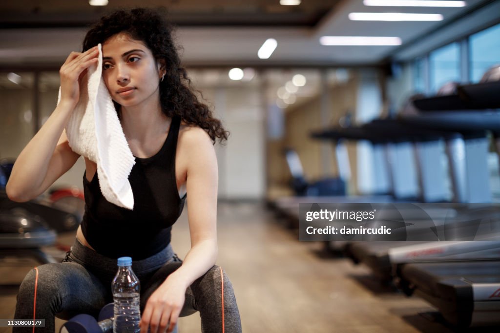 Young woman wiping sweat from forehead after exercise at the gym