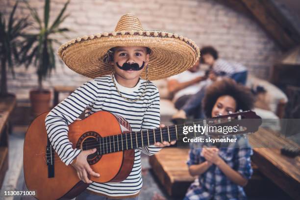 little mariachi boy playing a guitar at home. - sombrero stock pictures, royalty-free photos & images