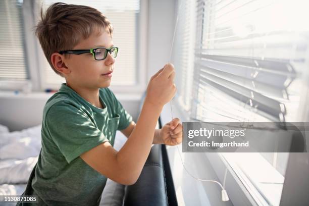 little boy opening the blinds in the morning - window blinds stock pictures, royalty-free photos & images