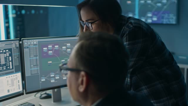 Male and Female IT Engineers / Programmers Having Discussion about Code Shown on Desktop Computer Displays. Displays Show Software Development / Code Writing / Website Design / Database Architecture
