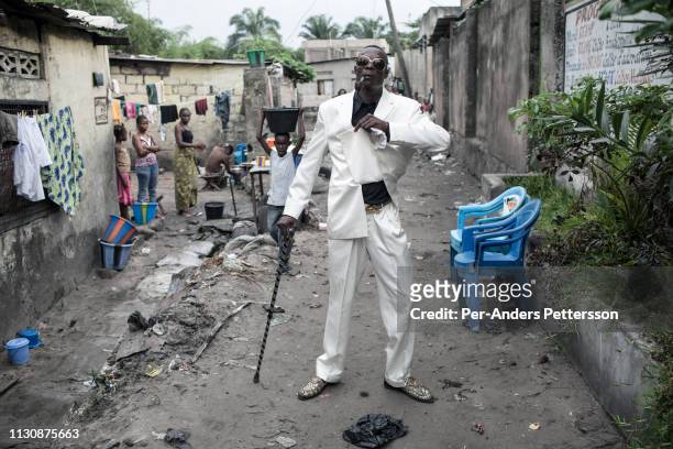 Jika, a senior Sapeur takes a walk in his white diamond suit close to his home in the Mombele area on February 12, 2012 in Kinshasa, DRC. Jika loves...