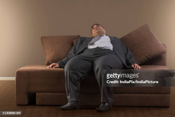 obese businessman in formal clothes sleeping on sofa at home - formal shirt stock pictures, royalty-free photos & images