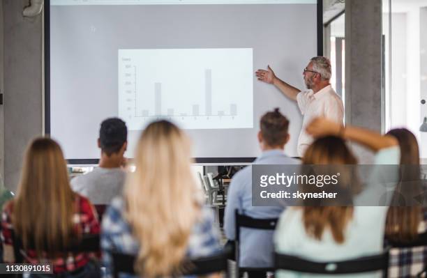 enseignant principal donnant une présentation au groupe d'étudiants universitaires à la salle de conférence. - projector classroom photos et images de collection