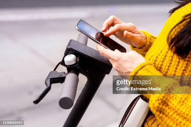 typing on a mobile phone while standing on an electric scooter - mobility scooter stock pictures, royalty-free photos & images