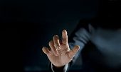 Business man pointing his finger on dark background, blank text.