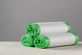 Three roll green eco garbage bag with copy space isolated on grey background.