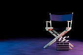 Director Chair and Movie Clapper with neon lights on black background