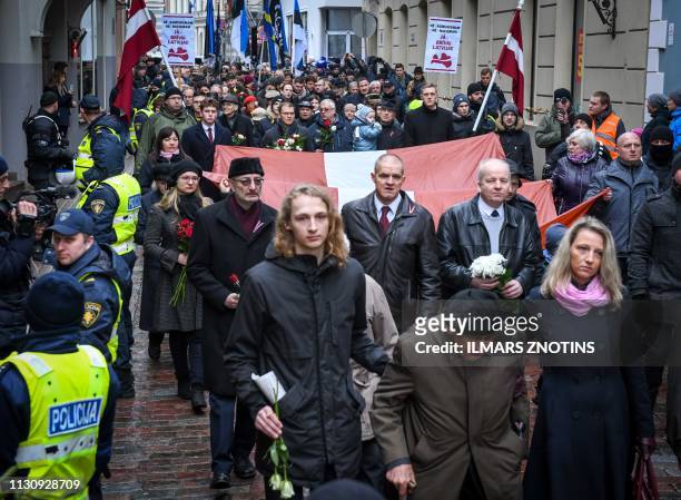 Veterans of the Latvian Legion, a force that was commanded by the German Nazi Waffen-SS during WWII, and their sympathizers carry flags and posters...