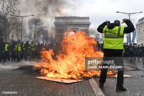 Yellow Vest protester gestures behind flames rising from a barricade, in Paris on March 16 during the 18th consecutive Saturday of demonstrations...