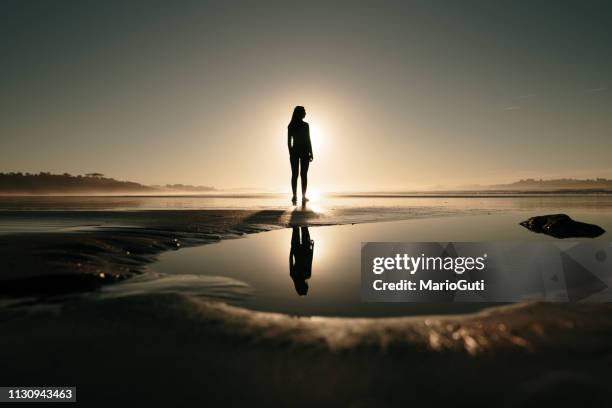 young woman at beach at sunset and her reflection - puddle reflection stock pictures, royalty-free photos & images