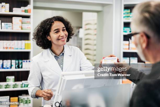 pharmacist handing customer his prescription - pharmacy stockfoto's en -beelden