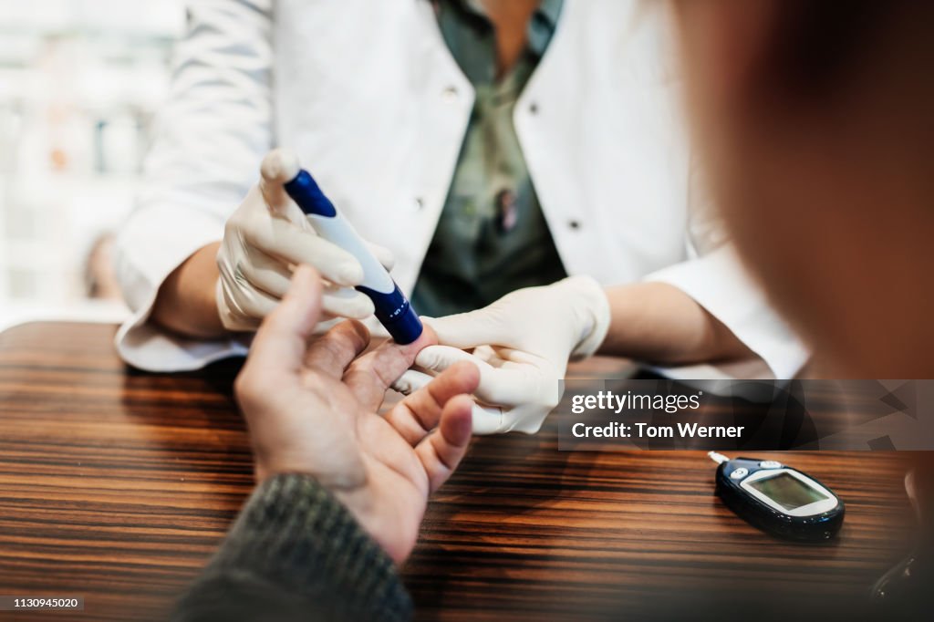 Pharmacist Checking Customer's Blood Sugar Levels