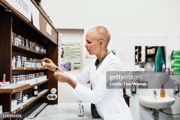 chemist sorting through medical ingredients - homeopathie stockfoto's en -beelden