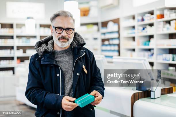 portrait of man holding prescription medicine. - pharmacy customer stock pictures, royalty-free photos & images