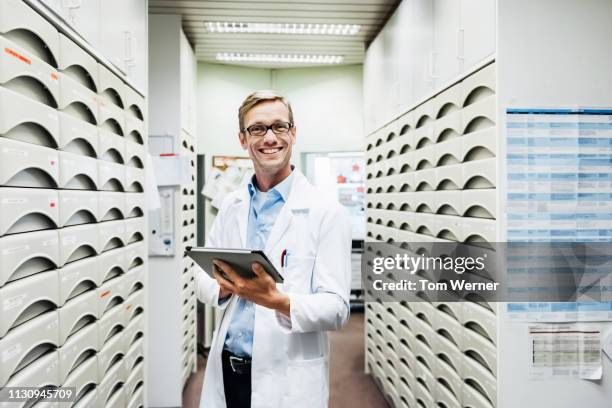 portrait of pharmacist standing in medical storage room - pharmacist stock-fotos und bilder