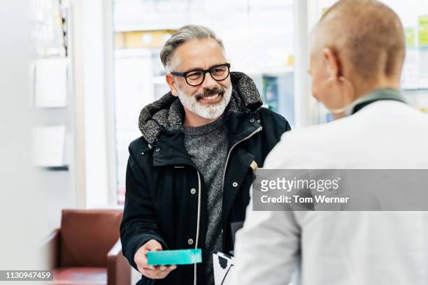 cheerful customer picking up his prescription - pharma people stockfoto's en -beelden