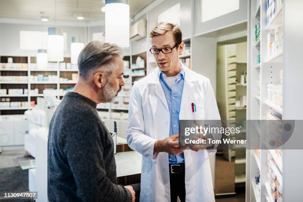 pharmacist advising customer on medicine instructions - prescription glasses stock pictures, royalty-free photos & images