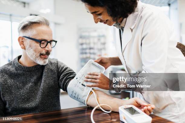 pharmacist measuring mature man's blood pressure - cinema society screening of you will meet a tall dark stranger arrivals stockfoto's en -beelden