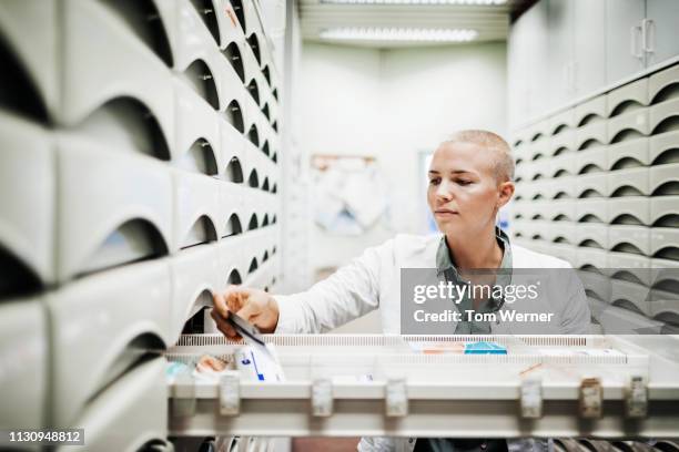 pharmacist searching drawers for customer's prescription - apothekerin stock-fotos und bilder