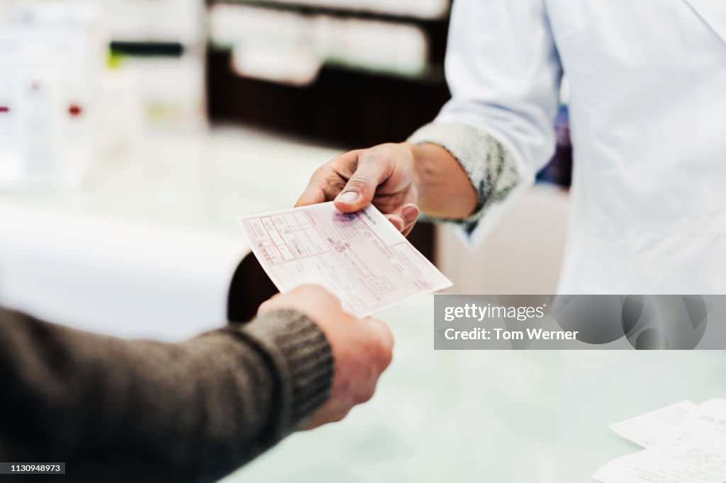 Customer Handing Prescription To Pharmacist