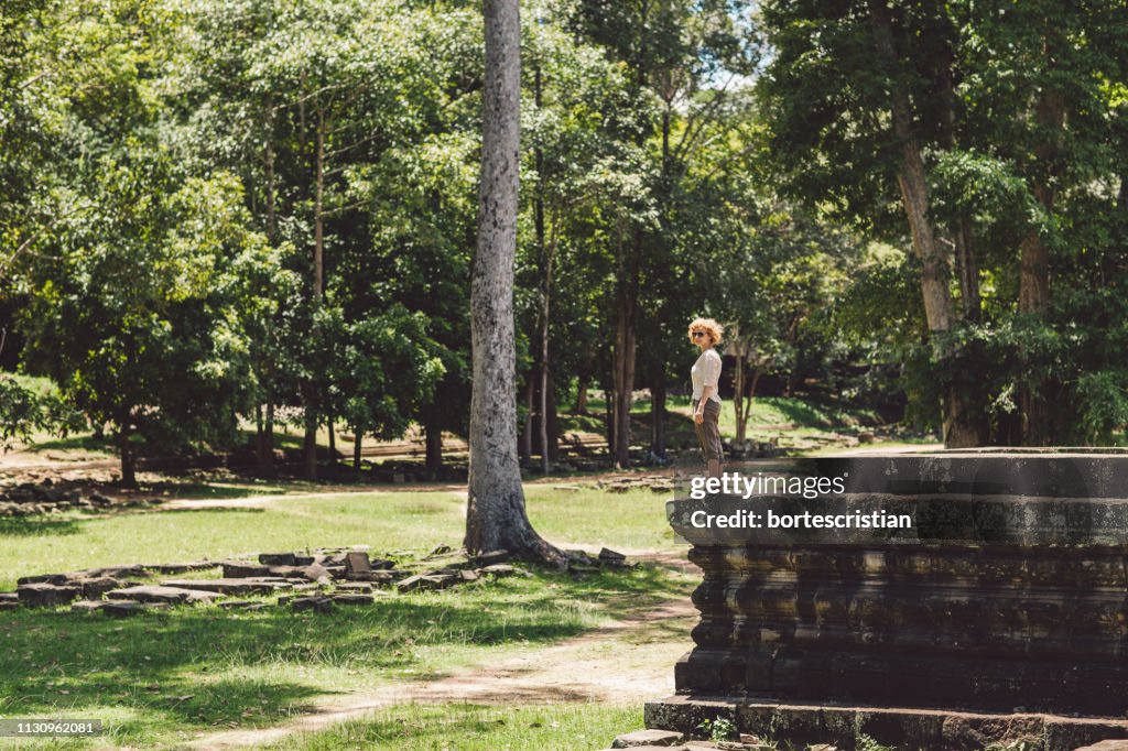 Side View Of Woman Standing By Trees In Park