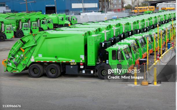 green garbage trucks in a row in parking lot - camión de la basura fotografías e imágenes de stock