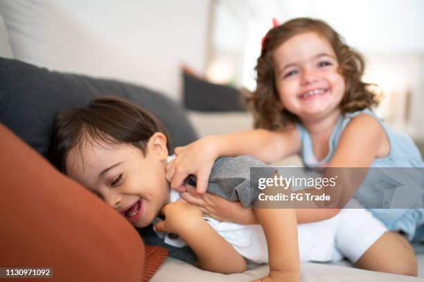 tweeling sibling (benedensyndroom broer en zuster) het kietelen bij bank - down syndrome baby stockfoto's en -beelden