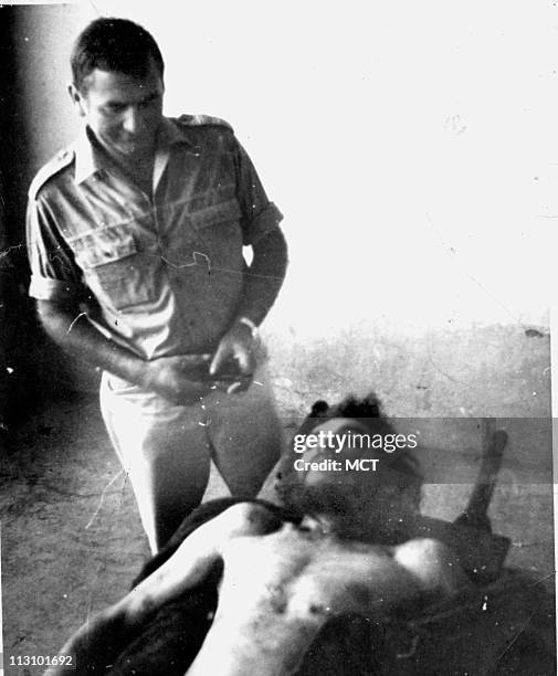 In this Erich Blossl photo, an unidentified man stands over the body of Che Guevara, who was executed in 1967 in La Higuera, Bolivia.