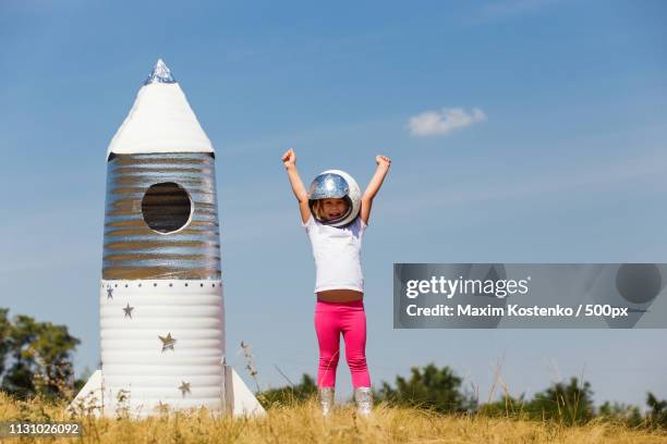 little girl with homemade rocket wearing astronaut helmet - toy rocket stock pictures, royalty-free photos & images