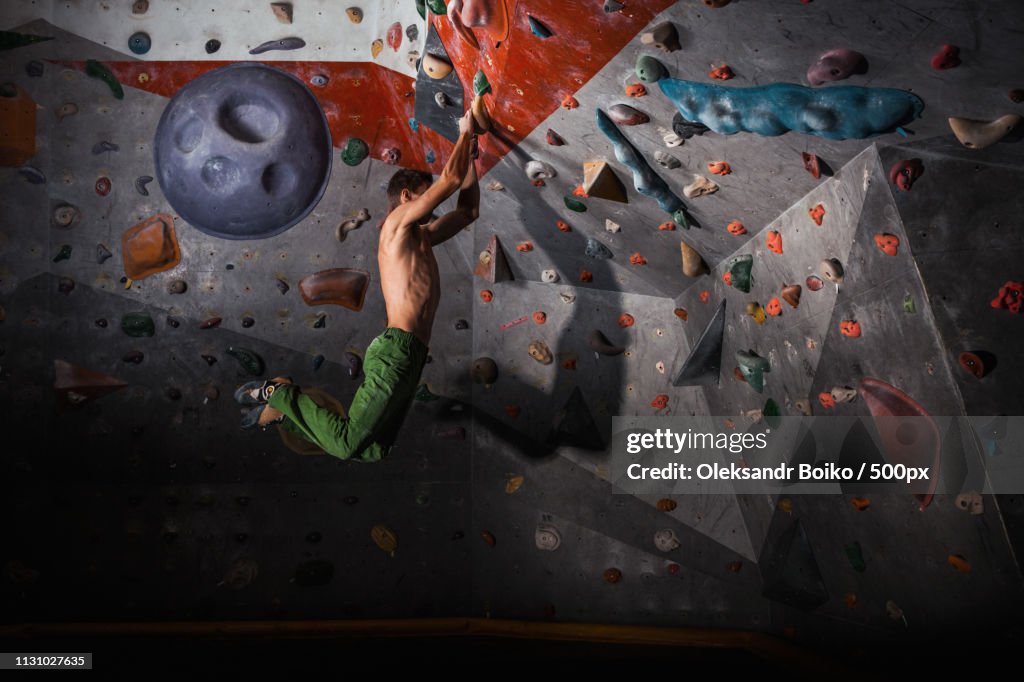 Man Practicing Rock-Climbing On A Rock Wall Indoors