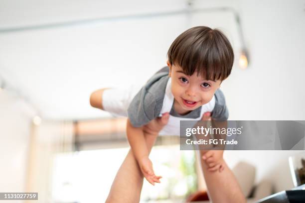 mother picking up her down syndrome son at home - down syndrome baby stock pictures, royalty-free photos & images