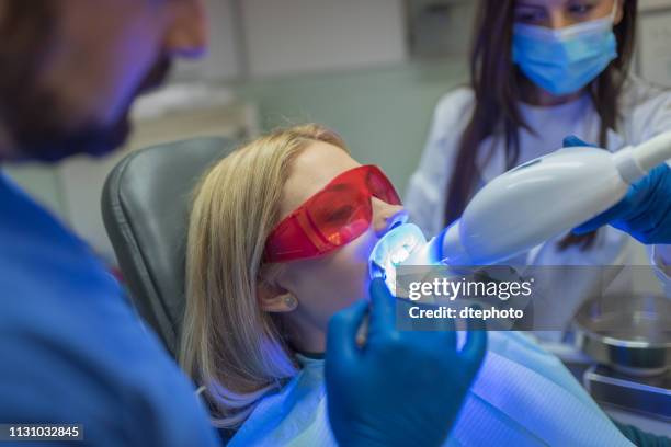 donna che sbianca i denti laser - sbiancamento dentale foto e immagini stock