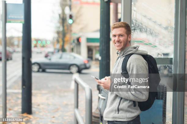 male in his 20s waiting for the bus at a city stop - s good morning america 2017 stock pictures, royalty-free photos & images