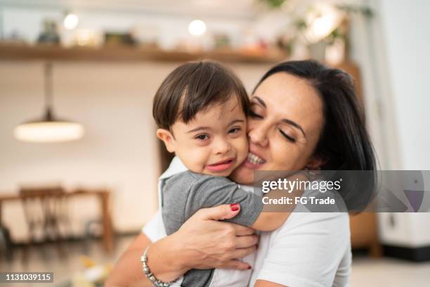 moeder en down syndroom zoon omarmen thuis - down syndrome baby stockfoto's en -beelden