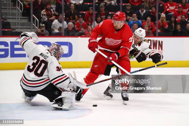 Anthony Mantha of the Detroit Red Wings tries to get a shot off between Cam Ward and Slater Koekkoek of the Chicago Blackhawks during overtime at...