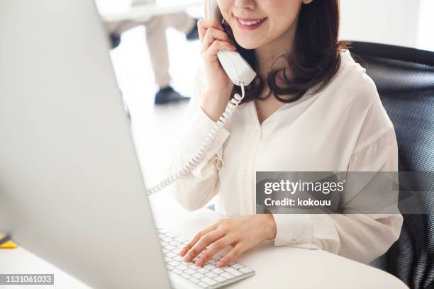女性マネージャーは、電話で顧客と話します - using phone ストックフォトと画像