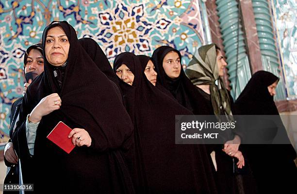 Iranian women stand in line at a mosque in Tehran that was transformed into a polling station as they wait to cast their ballots in the presidential...