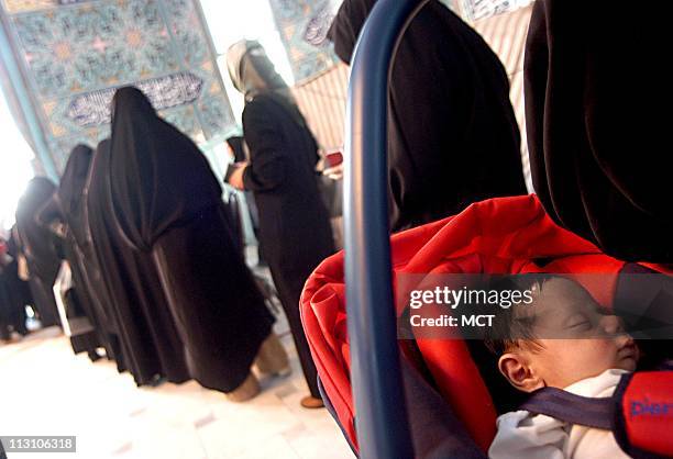 Iranian housewives carry their children as they stand in line at to cast their ballots in the presidential run-off between Akbar Hashemi Rafsanjani...