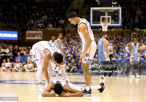 Teammates Tre Jones and Jordan Goldwire check on Javin DeLaurier of the Duke Blue Devils during their game against the North Carolina Tar Heels at...