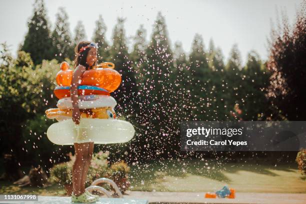 happy girl with several inflatable rings ready to jump in pool - recreational pursuit photos et images de collection