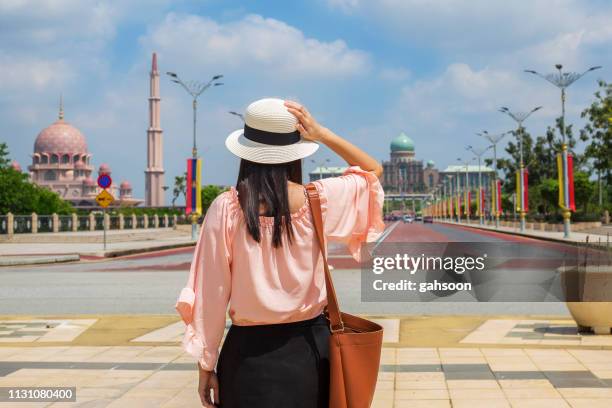 vista posterior de las mujeres jóvenes asiáticas que viajan caminando y mirando alrededor de la zona de putrajaya, con el fondo de la mezquita islámica y la oficina de administración del primer ministro de malasia - estado de selangor fotografías e imágenes de stock