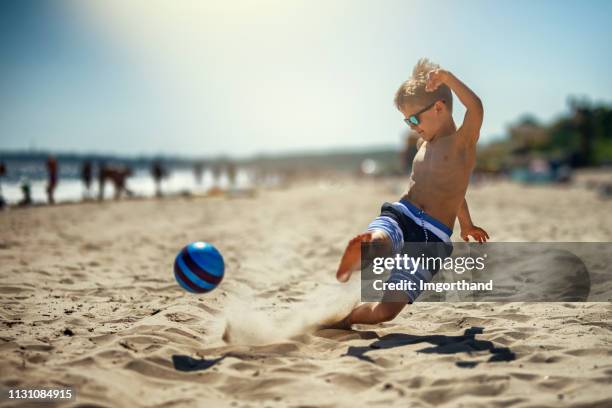 kleine jongen voetballen op het strand - sand trap stockfoto's en -beelden