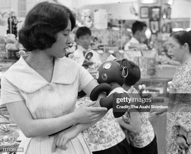 Young woman purchases a Dakko-Chan doll on July 29, 1960 in Tokyo, Japan.