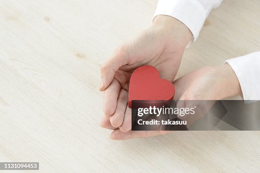 Heart object covered by female hands Heart object covered by female hands