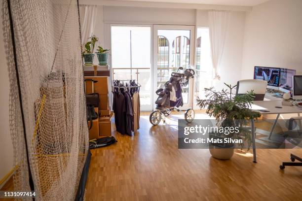 golf net and bag and home office with cardboard box in living room - golf club house stock pictures, royalty-free photos & images