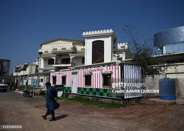 In this picture taken on March 12 a Pakistani man walks past a closed medical dispensary of banned militant Jamaat-ud-Dawa -- an organisation...