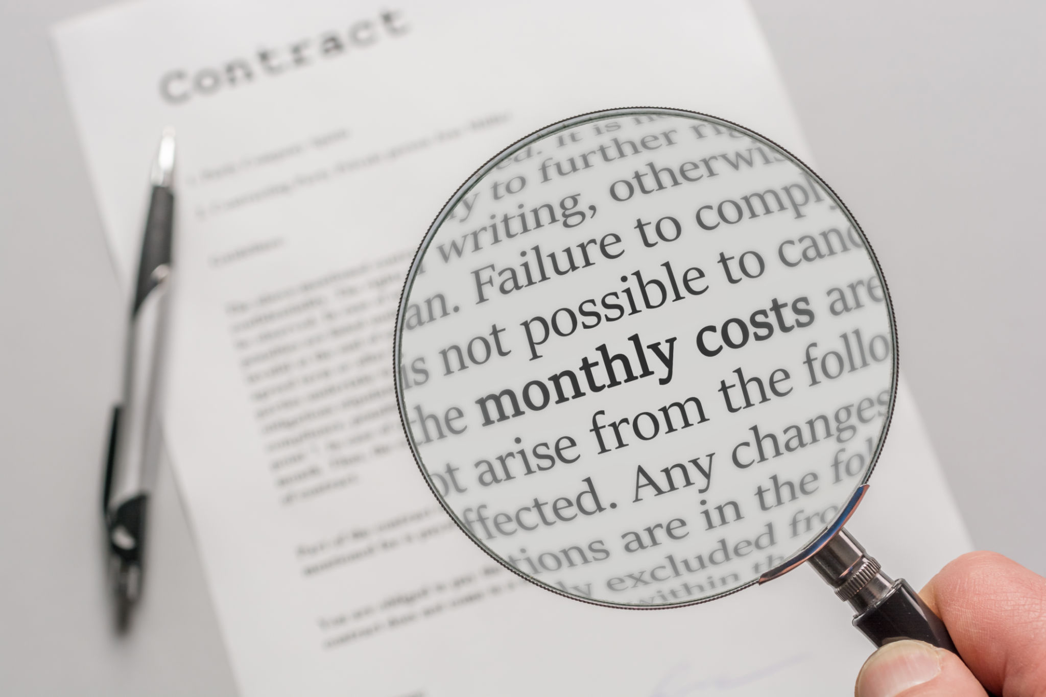 Contract is checked with a magnifying glass on the subject of monthly costs as a result of a contract Contract is checked with a magnifying glass on the subject of monthly costs as a result of a contract