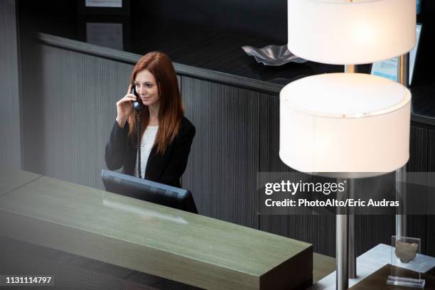 female receptionist talking on telephone - reception stock-fotos und bilder